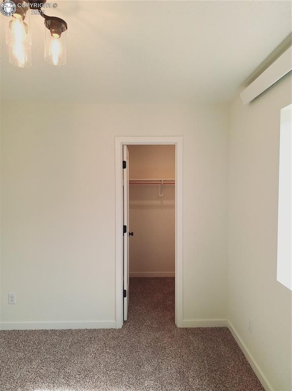 138 Jerry Dr, Westcliffe, CO 81252 - unfurnished bedroom with a closet, a chandelier, baseboards, carpet floors, and a walk in closet