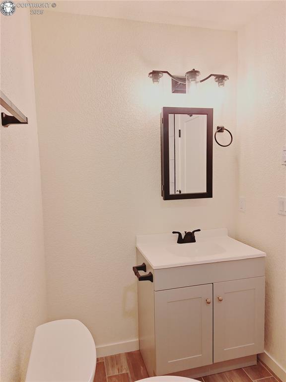 138 Jerry Dr, Westcliffe, CO 81252 - half bath featuring baseboards, wood finished floors, toilet, and vanity