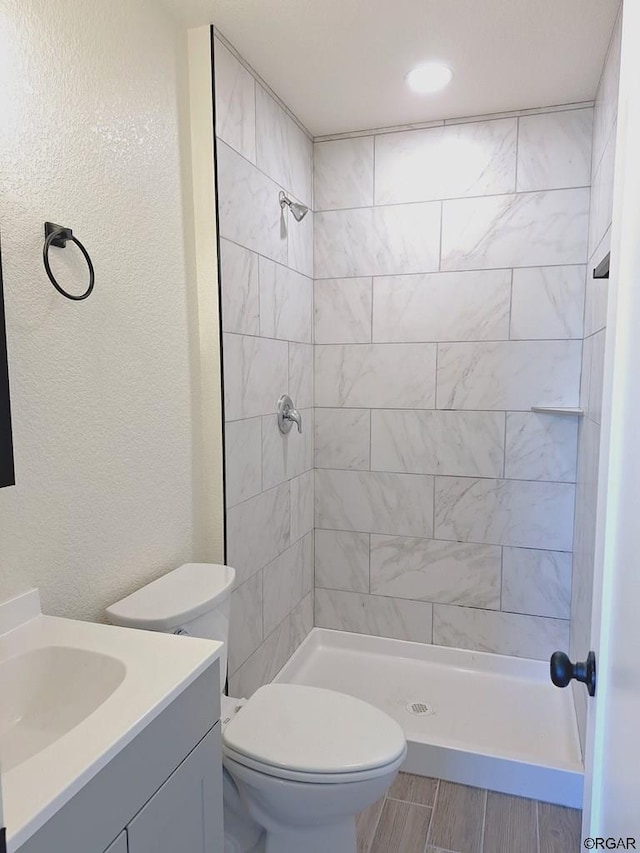 bathroom with vanity, tiled shower, and toilet