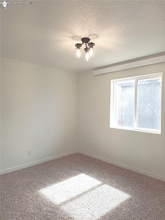 138 Jerry Dr, Westcliffe, CO 81252 - spare room featuring baseboards, carpet flooring, a textured ceiling, and a notable chandelier