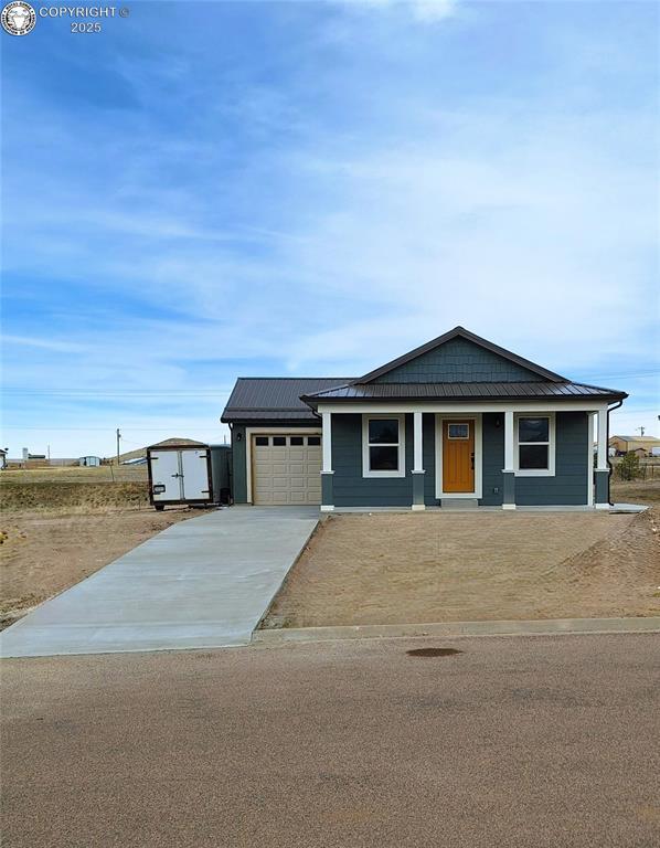 138 Jerry Dr, Westcliffe, CO 81252 - view of front of house with metal roof, a storage shed, a garage, and concrete driveway