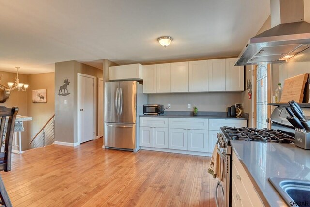 kitchen with hanging light fixtures, island exhaust hood, appliances with stainless steel finishes, and white cabinets