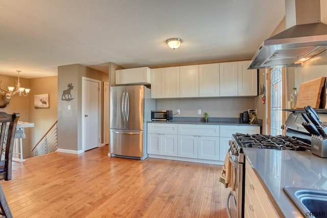 kitchen with hanging light fixtures, island exhaust hood, appliances with stainless steel finishes, and white cabinets