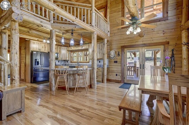 540 County Road 356, Westcliffe, CO 81252 - dining space with french doors, a ceiling fan, light wood-type flooring, wooden walls, and a high ceiling