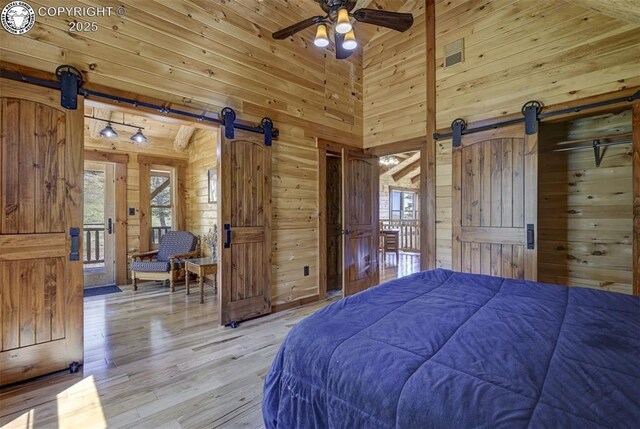 540 County Road 356, Westcliffe, CO 81252 - bedroom with a barn door, wood walls, light wood-style floors, and a high ceiling