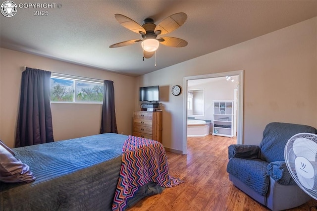 bedroom featuring ceiling fan, baseboards, ensuite bathroom, and wood finished floors