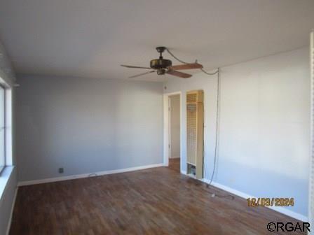 unfurnished room featuring wood finished floors, a ceiling fan, and baseboards