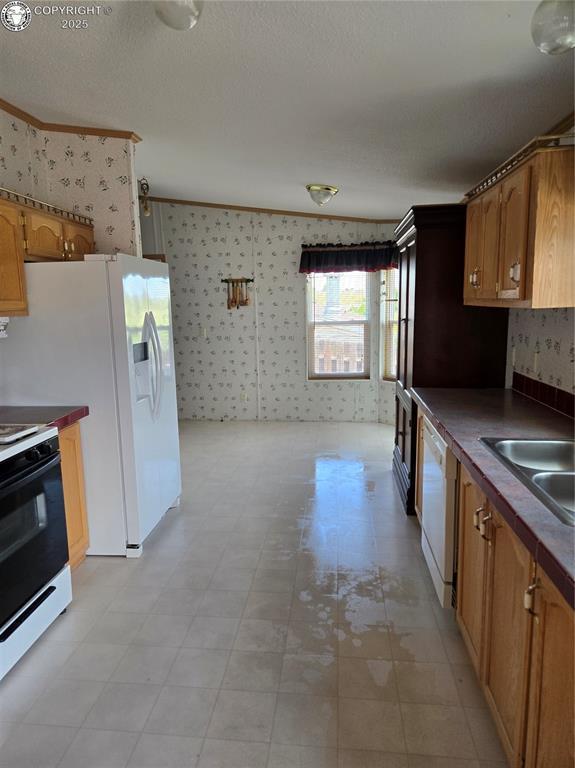 213 Indian Hills Rd, Florence, CO 81226 - kitchen with wallpapered walls, white appliances, dark countertops, brown cabinetry, and light flooring