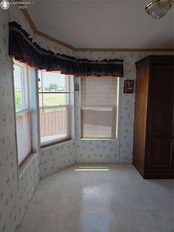 213 Indian Hills Rd, Florence, CO 81226 - unfurnished room with wallpapered walls, healthy amount of natural light, light flooring, and crown molding