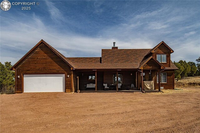 252 Apache Trl, Cotopaxi, CO 81223 - view of front of house featuring driveway, a porch, an attached garage, a shingled roof, and a chimney