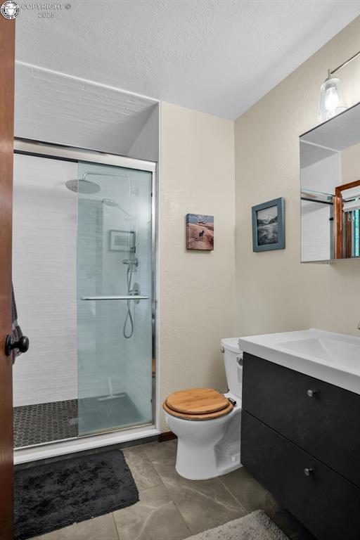 1124 Grand Ave, Canon City, CO 81212 - full bath with vanity, a stall shower, a textured ceiling, and tile patterned floors