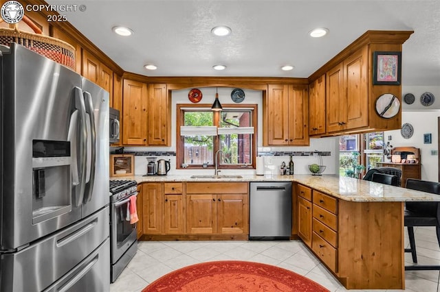 1124 Grand Ave, Canon City, CO 81212 - kitchen featuring appliances with stainless steel finishes, a peninsula, a breakfast bar area, light stone countertops, and brown cabinets
