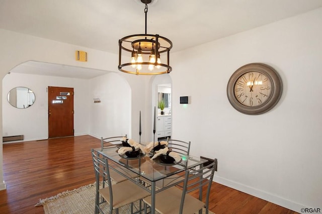 dining space with a baseboard heating unit, an inviting chandelier, and dark hardwood / wood-style floors