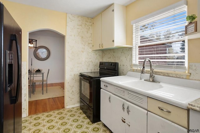 kitchen featuring sink, black appliances, and white cabinets