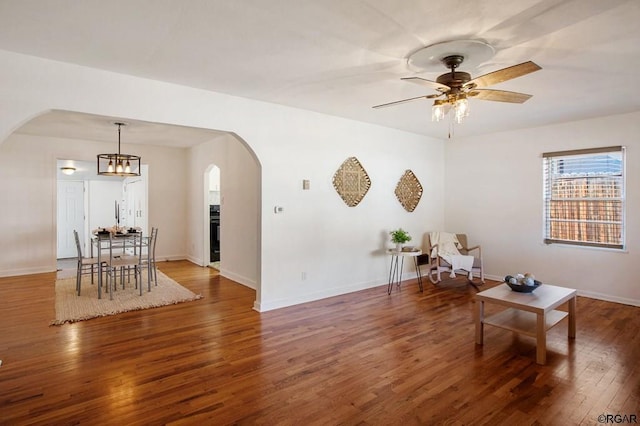 sitting room with ceiling fan with notable chandelier and dark hardwood / wood-style flooring