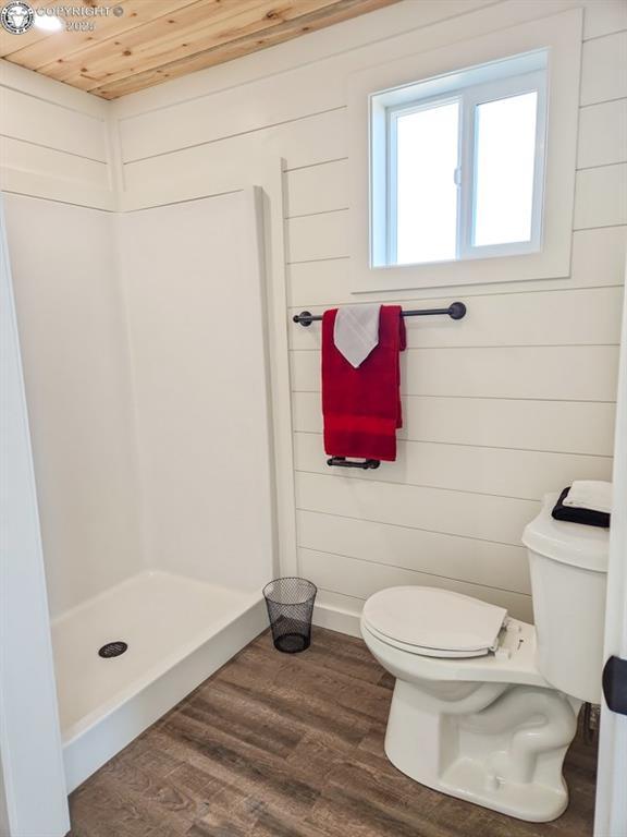 bathroom featuring wooden ceiling, a shower stall, toilet, and wood finished floors