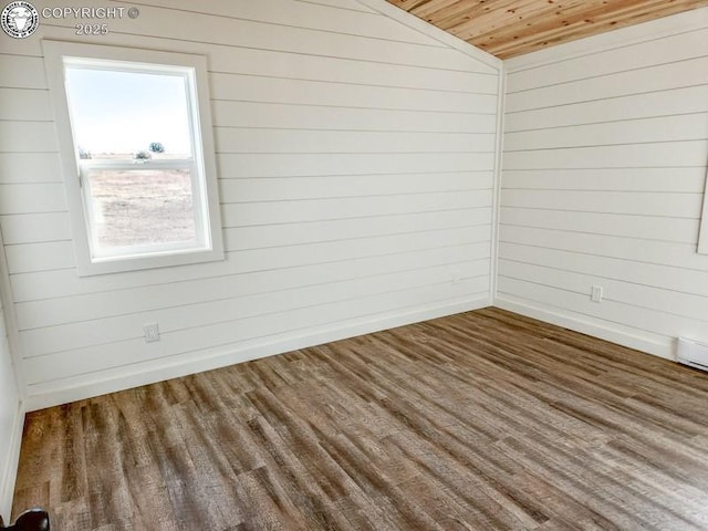 spare room featuring baseboards, wood ceiling, wood finished floors, and wooden walls