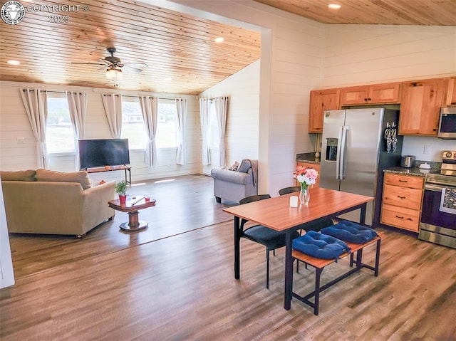 dining area with wood finished floors, ceiling fan, wooden walls, wood ceiling, and vaulted ceiling