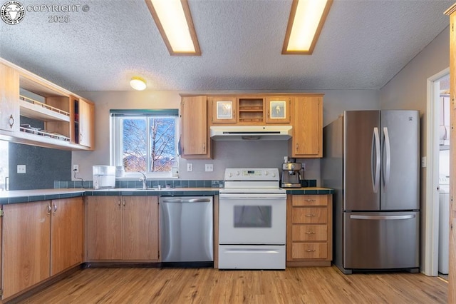 kitchen featuring appliances with stainless steel finishes, light wood-type flooring, tile counters, and a textured ceiling