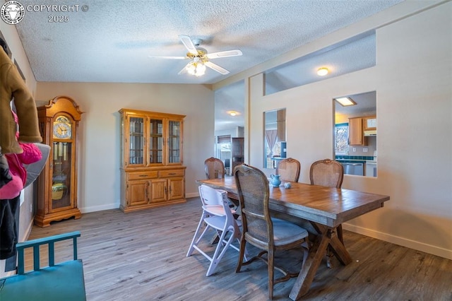 dining space with lofted ceiling, a textured ceiling, light hardwood / wood-style flooring, and ceiling fan