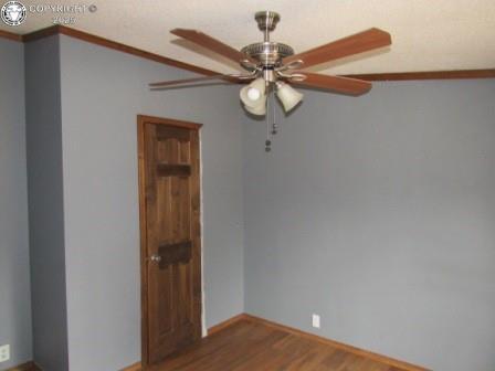unfurnished room with crown molding, baseboards, a ceiling fan, and wood finished floors