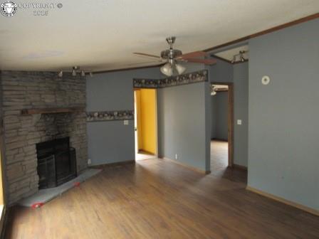 unfurnished living room featuring baseboards, a fireplace, ceiling fan, and wood finished floors