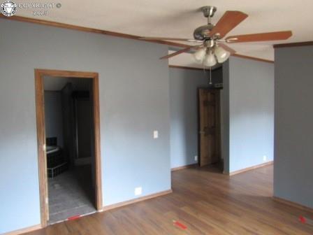 empty room featuring ornamental molding, baseboards, a ceiling fan, and wood finished floors