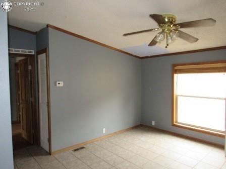 spare room featuring ornamental molding, baseboards, and a ceiling fan