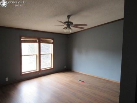 unfurnished room featuring a ceiling fan, ornamental molding, a textured ceiling, and wood finished floors