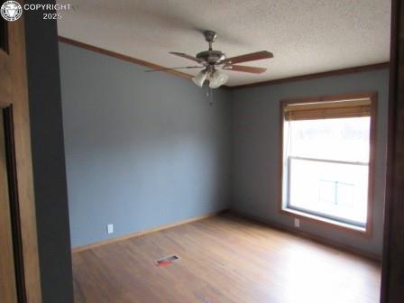 spare room featuring a ceiling fan, visible vents, light wood-type flooring, and a textured ceiling