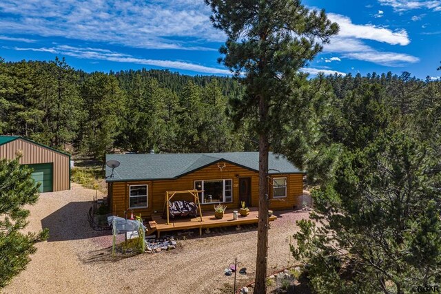 back of property featuring a wooden deck, a garage, and an outdoor structure