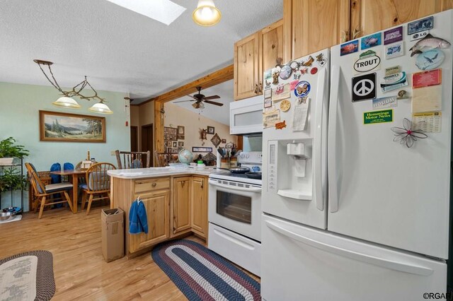 kitchen featuring hanging light fixtures, white appliances, a textured ceiling, and light wood-type flooring