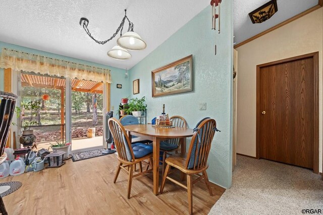 dining space with hardwood / wood-style flooring, lofted ceiling, and a textured ceiling