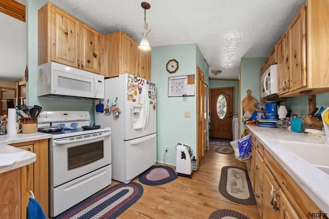 kitchen featuring sink, a textured ceiling, pendant lighting, white appliances, and light hardwood / wood-style floors