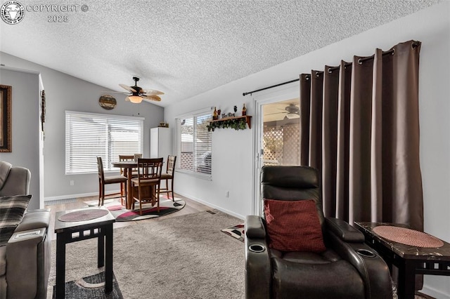 living room featuring baseboards, a textured ceiling, a ceiling fan, and vaulted ceiling