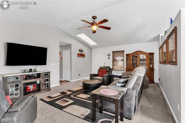 carpeted living room featuring lofted ceiling with skylight, a textured ceiling, baseboards, and ceiling fan