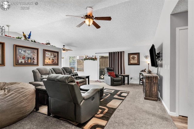 carpeted living area featuring lofted ceiling, a ceiling fan, baseboards, and a textured ceiling