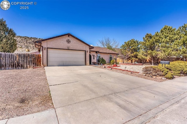 ranch-style house featuring an attached garage, fence, driveway, and stucco siding