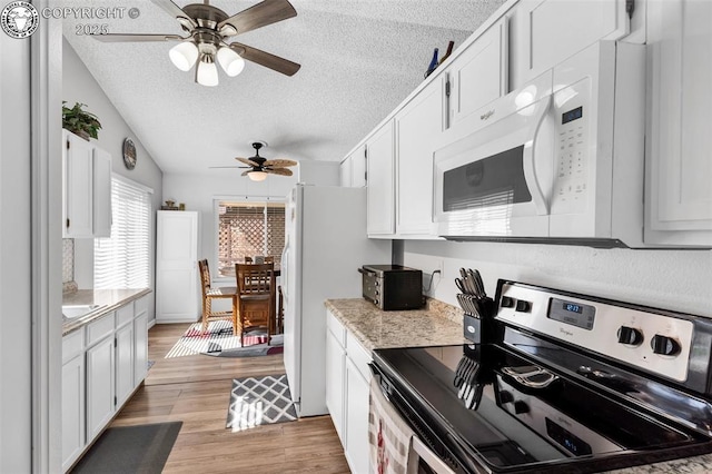 kitchen with white microwave, light wood finished floors, light countertops, stainless steel range with electric stovetop, and a textured ceiling