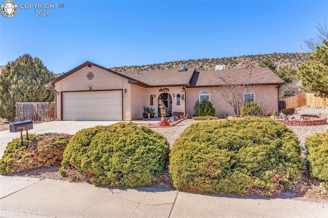 ranch-style house with stucco siding, concrete driveway, a garage, and fence