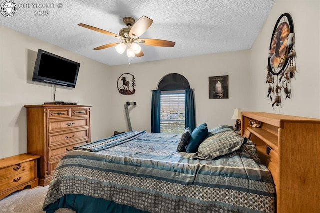 carpeted bedroom featuring ceiling fan and a textured ceiling