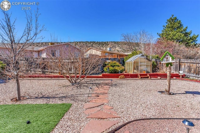 view of yard featuring an outbuilding, a greenhouse, and fence