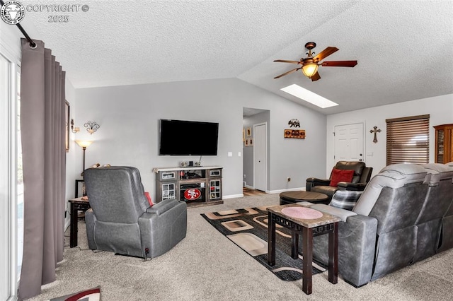 living area with baseboards, vaulted ceiling with skylight, ceiling fan, a textured ceiling, and light carpet