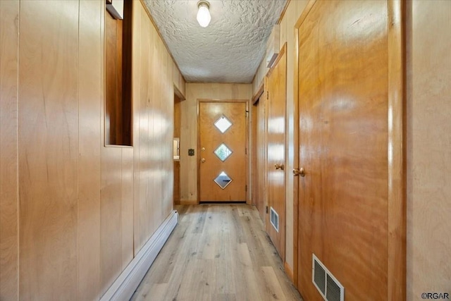 entryway featuring wooden walls, light hardwood / wood-style floors, and a textured ceiling