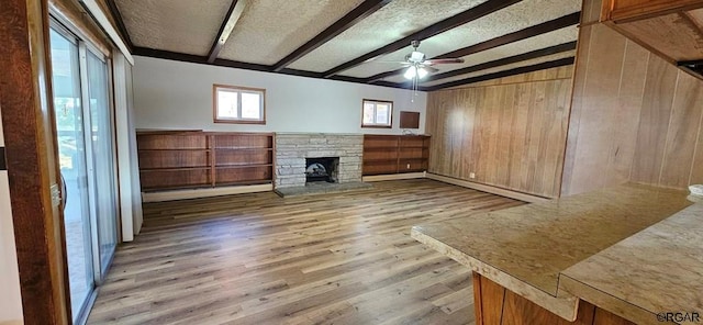 unfurnished living room with wood walls, light hardwood / wood-style flooring, a baseboard radiator, ceiling fan, and a fireplace