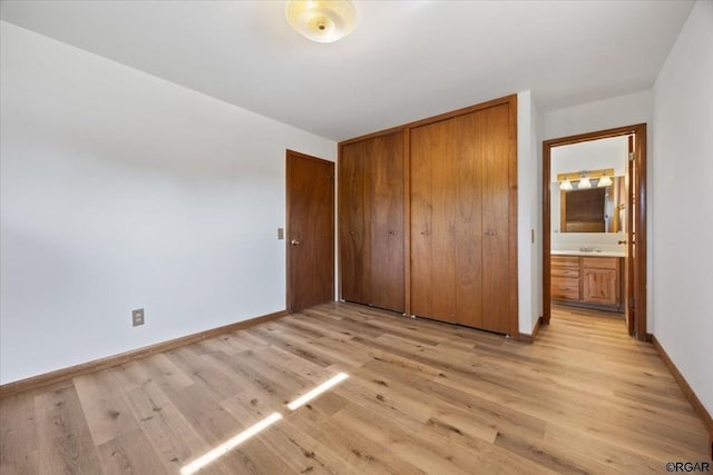 unfurnished bedroom featuring ensuite bathroom, light hardwood / wood-style floors, and a closet