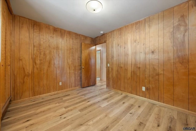 empty room with wooden walls and light hardwood / wood-style floors