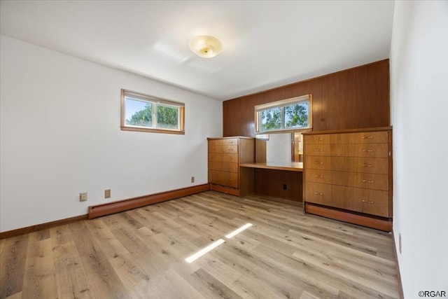 unfurnished bedroom with baseboard heating, multiple windows, and light hardwood / wood-style flooring