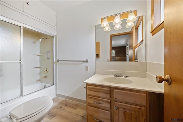 full bathroom with vanity, bath / shower combo with glass door, toilet, and wood-type flooring