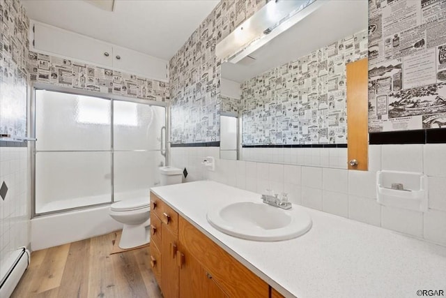 full bathroom featuring toilet, wood-type flooring, shower / bath combination with glass door, tile walls, and a baseboard radiator